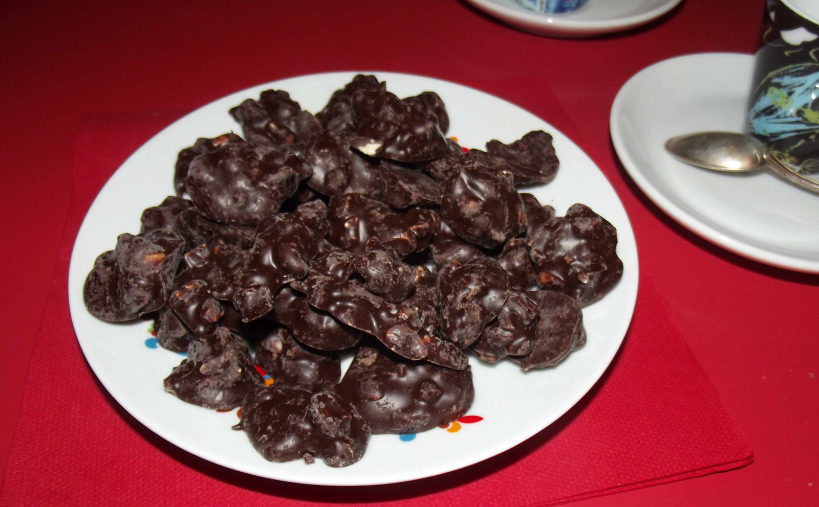 Baci di Cherasco de chocolate e avelãs em um prato branco sobre uma mesa vermelha