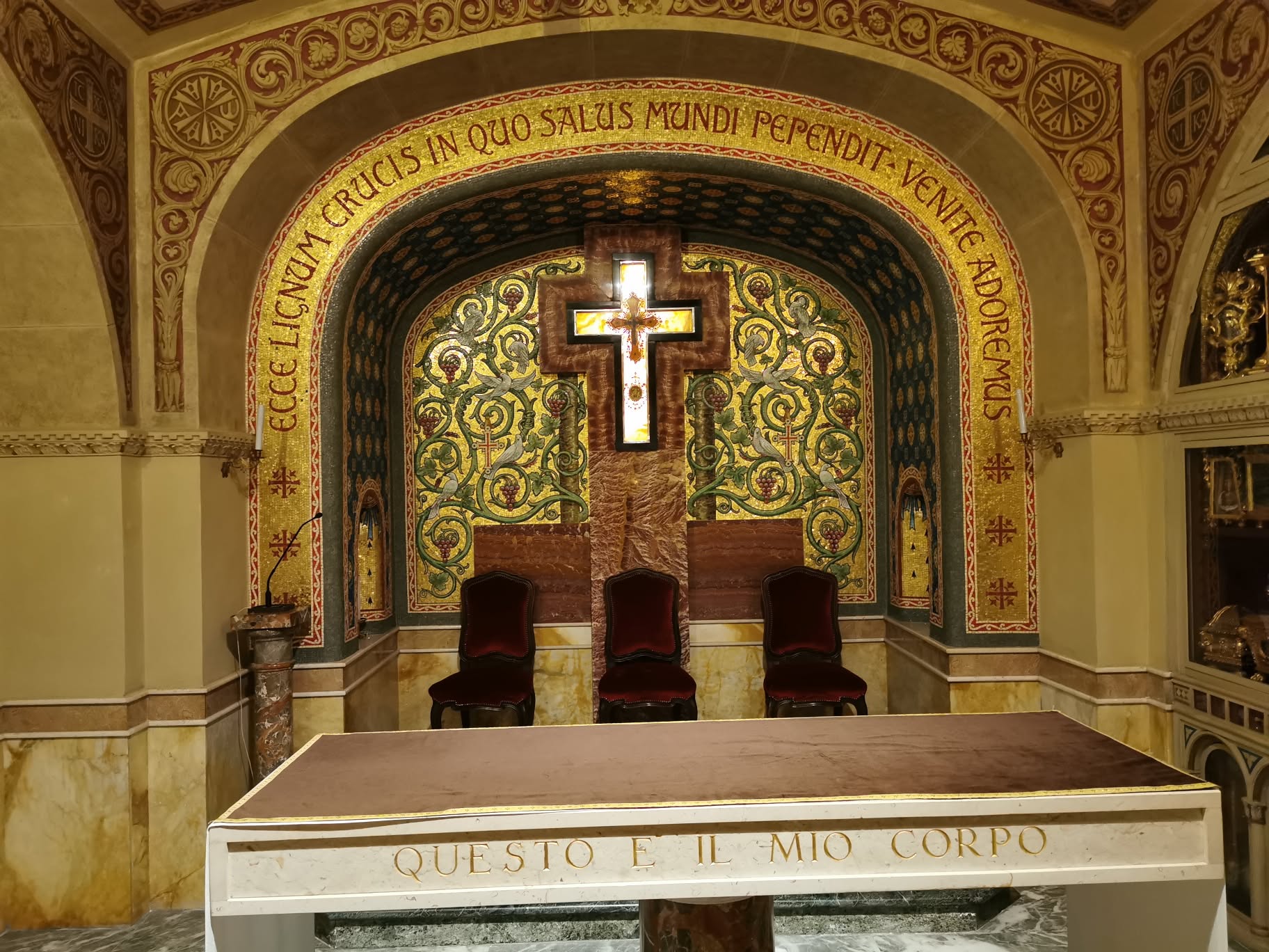 Altar com cruz luminosa e inscrição latina na Capela das Relíquias