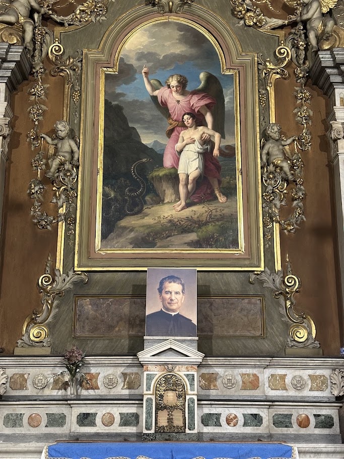 Pintura de um anjo acompanhando uma criança sobre o altar, com um retrato de Dom Bosco abaixo
