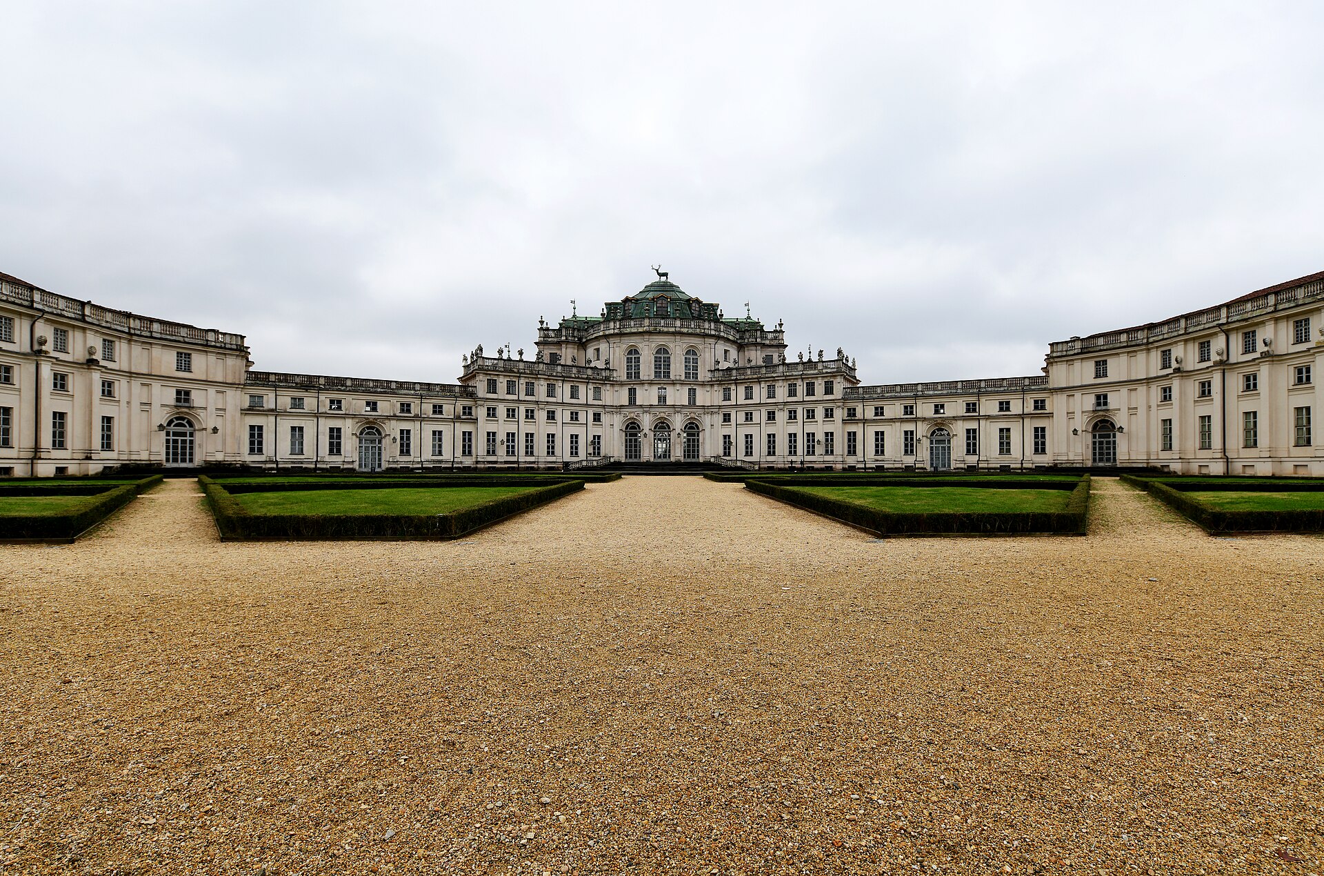 Fachada da Palazzina di Caccia di Stupinigi, com corpo central encimado por um cervo, alas laterais e canteiros geométricos.