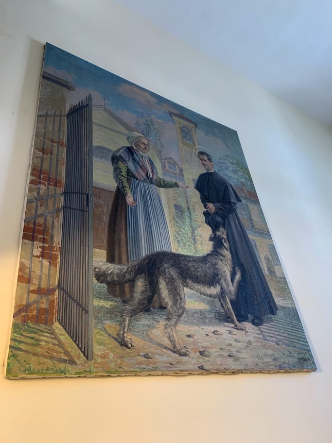 Quadro com Dom Bosco e Grigio exposto na escadaria do Museu Casa Dom Bosco