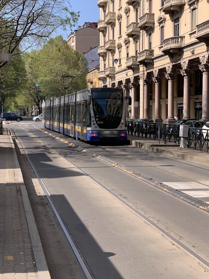 Bonde moderno circulando por uma rua de Turim junto a edifícios com pórticos