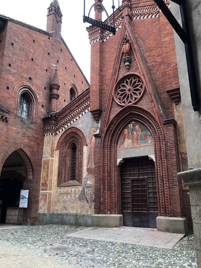 Fachada de igreja gótica em tijolos com rosácea e pinturas acima da porta