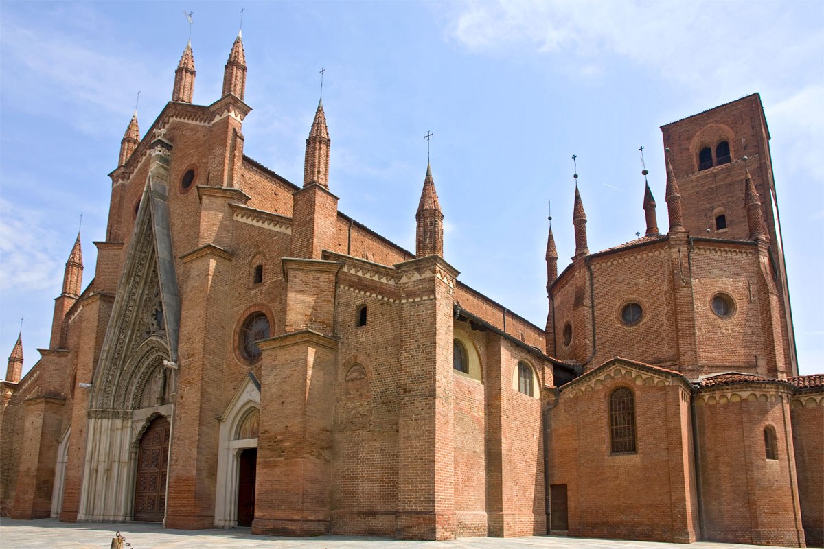 Fachada de tijolos do Duomo de Chieri, com pináculos, portal e torre lateral