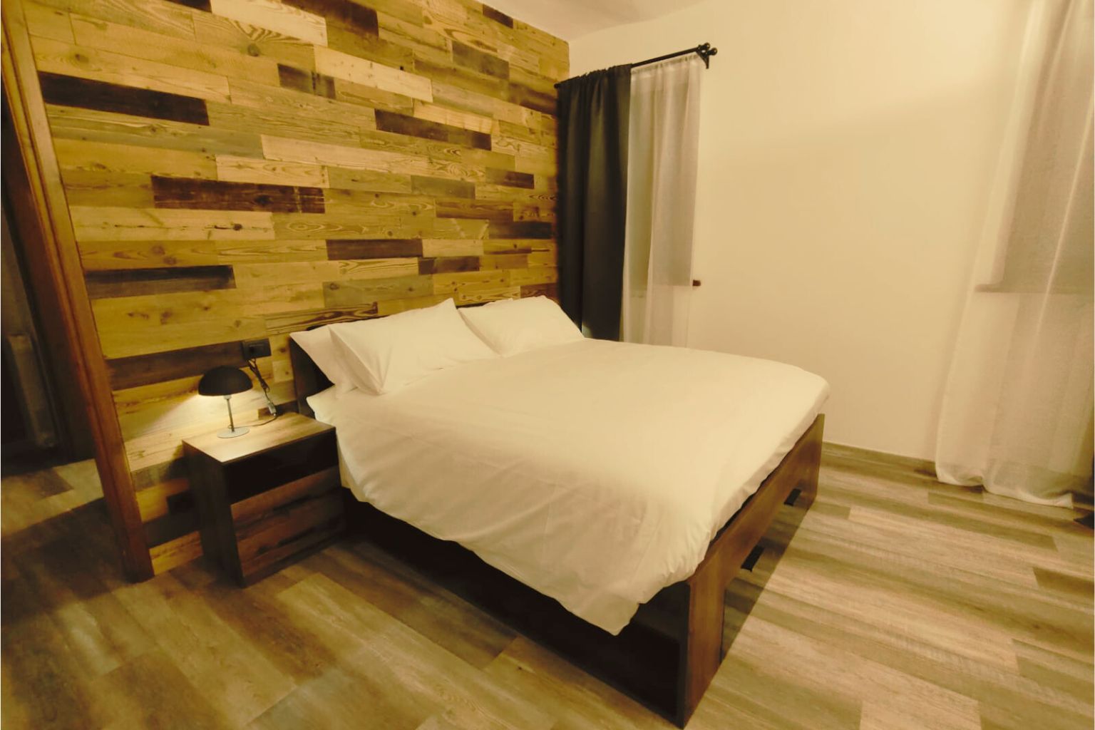 Quarto da La Bessolina com cama de casal e parede de madeira