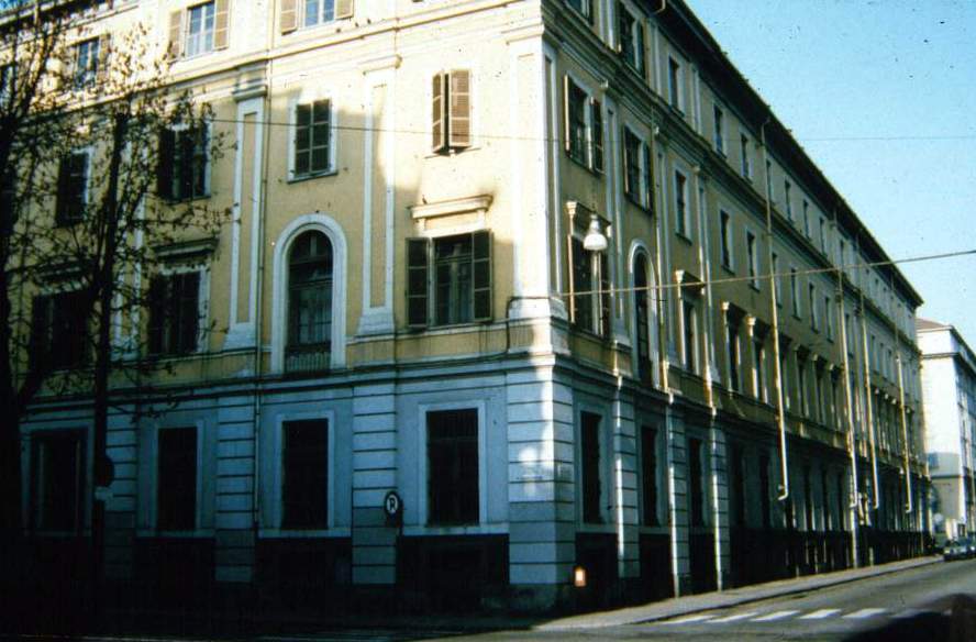Edifício do Collegio Artigianelli em uma esquina de Turim, com fachadas claras, janelas e arcos altos.