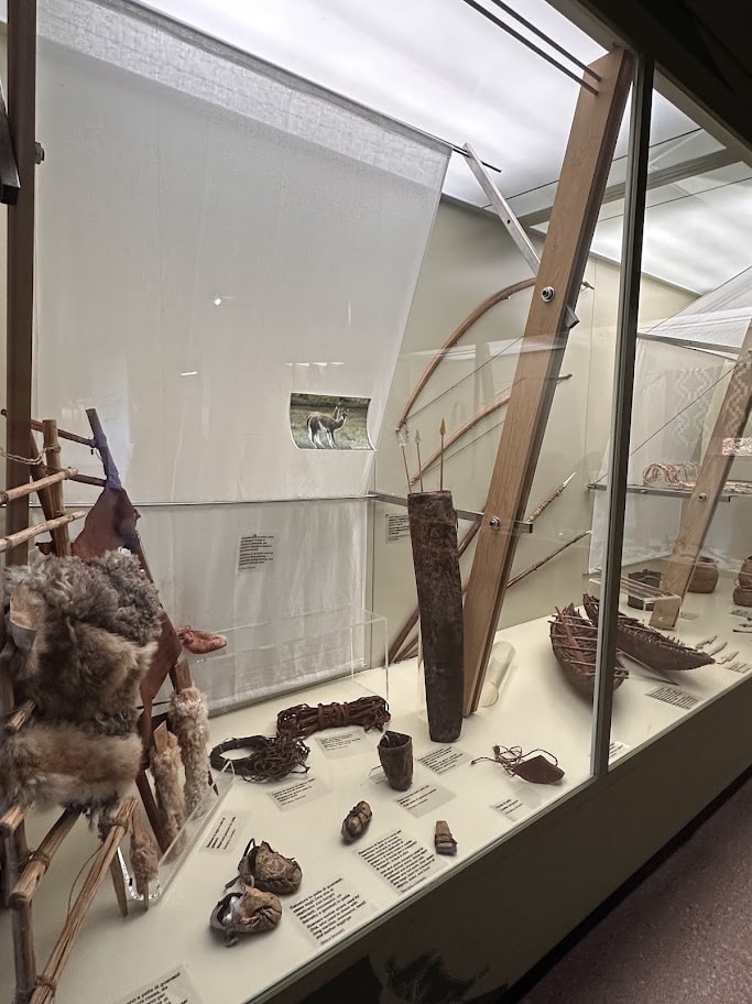 Arcos, flechas e pequenos objetos expostos em vitrine