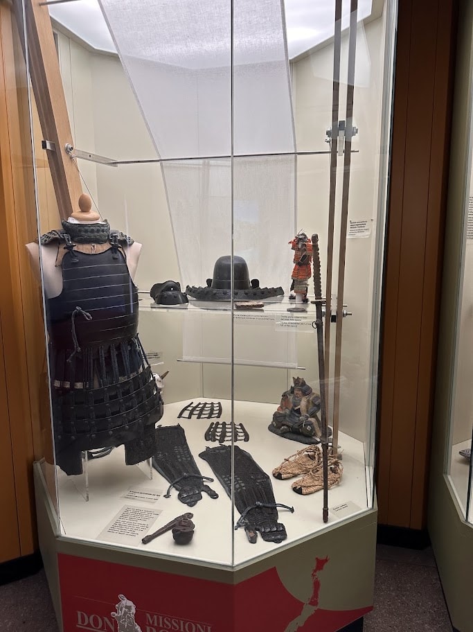 Armadura, capacetes e objetos na vitrine identificada pelo mapa do Japão