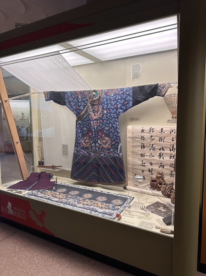 Traje azul bordado e rolo com caligrafia na seção chinesa