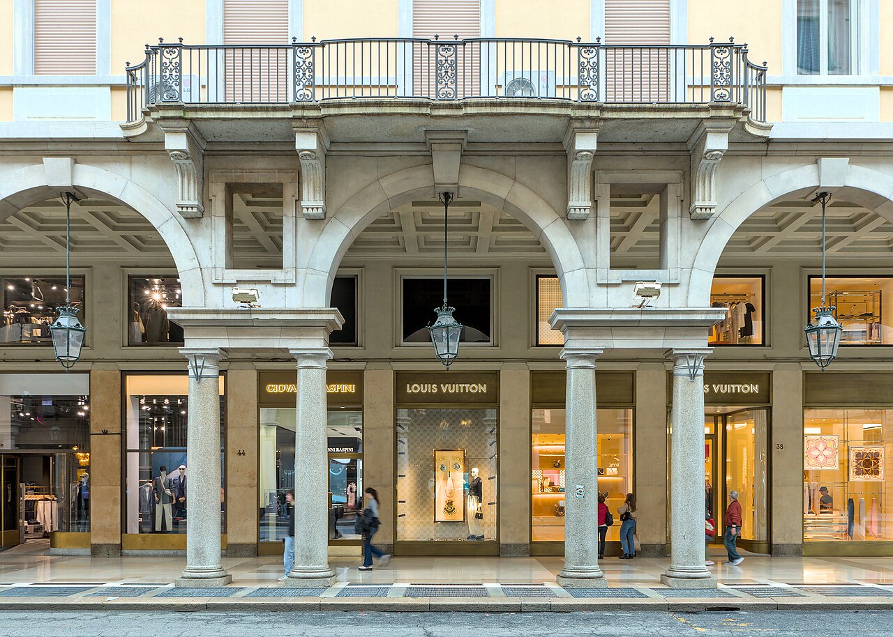 Colunas e arcos dos pórticos de Via Roma, com vitrines e pedestres em Turim