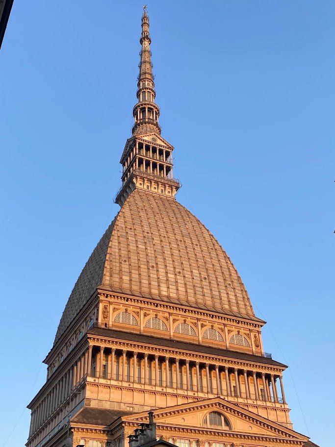 Cúpula e pináculo da Mole Antonelliana iluminados pelo sol, sob céu azul